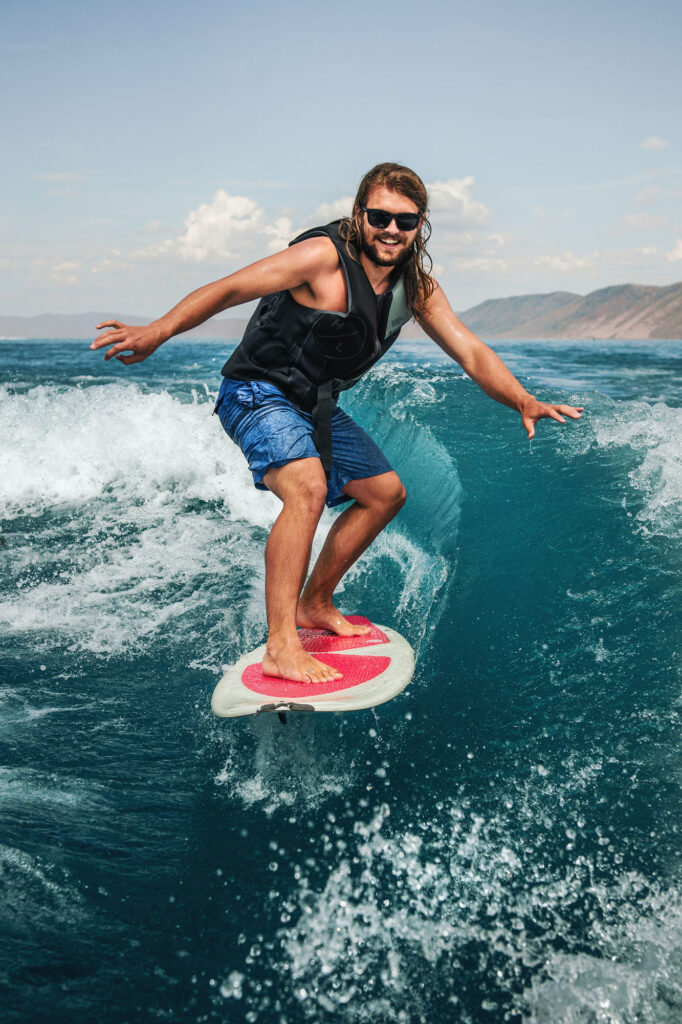 A smiling wakesurfer surfing the wake on Lake Tahoe.